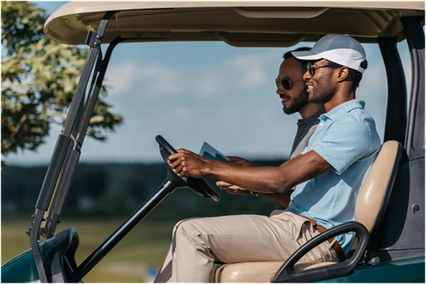 Smiling friends talking while riding golf cart